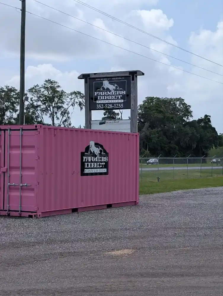 Pink Farmers Direct shipping container alongside a road sign