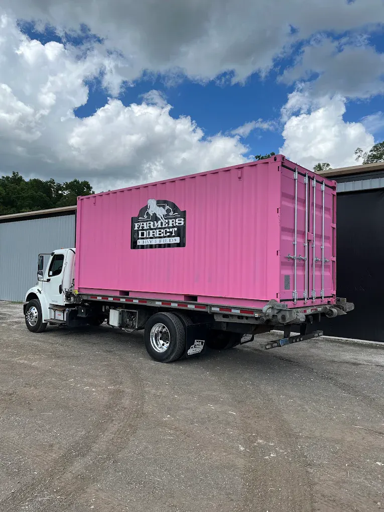 Pink branded Farmers Direct shipping container loaded on a delivery truck