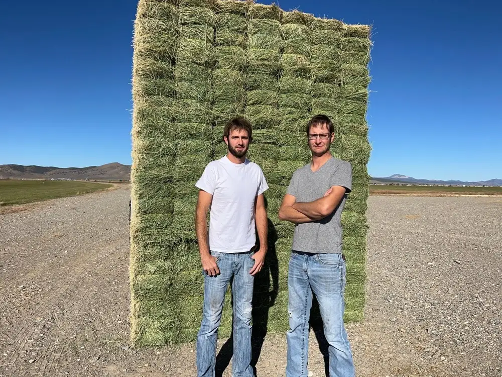 Delmar and Trennis, owners of Farmers Direct Hay and Feed, standing in front of hay bales in Nevada