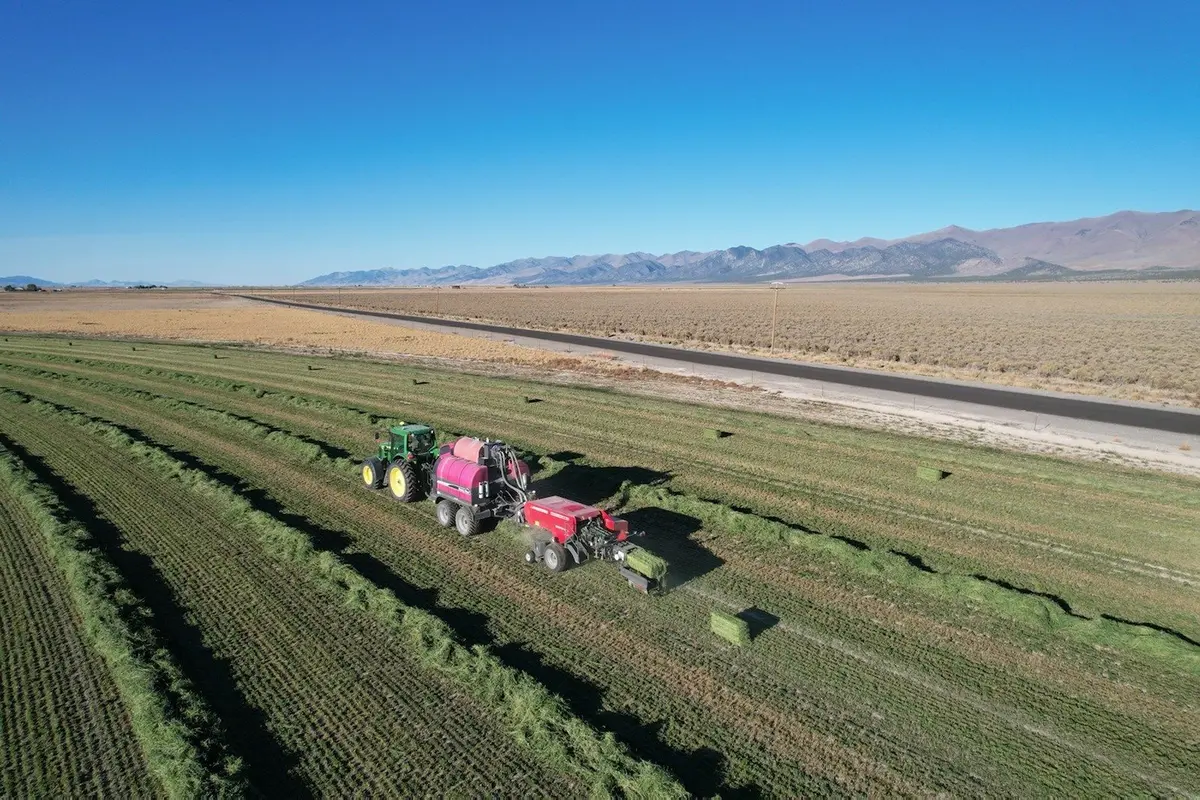 Aerial drone shot of tractor baling hay in a Nevada field